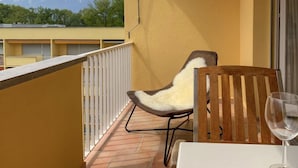 Ein Balkon mit Stuhl und Tisch, einem Weinglas und Blick auf die Berge.
