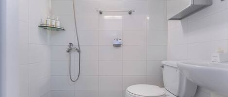 Un baño moderno con ducha, inodoro y un estante con artículos de aseo.