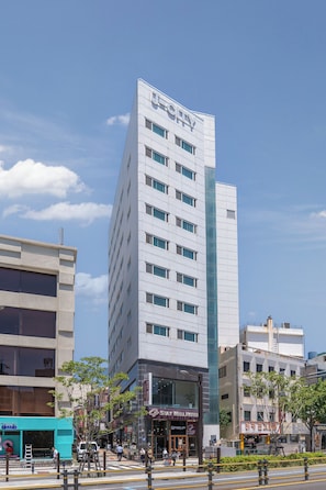 A modern hotel with a prominent 'U' logo, multiple floors, and a glass facade. - Staywell Hotel (Busan)