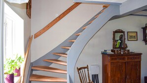 Un escalier en colimaçon avec des marches en bois et une rampe bleue, menant à l’étage supérieur.
