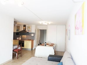 Un espace de vie compact comprenant une kitchenette, un coin repas et un canapé.