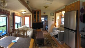 Un espacio habitable compacto con sofá, mesa de comedor, televisor, refrigerador y estufa.