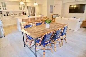 A modern kitchen with white cabinets, a wooden dining table, and blue wicker chairs.