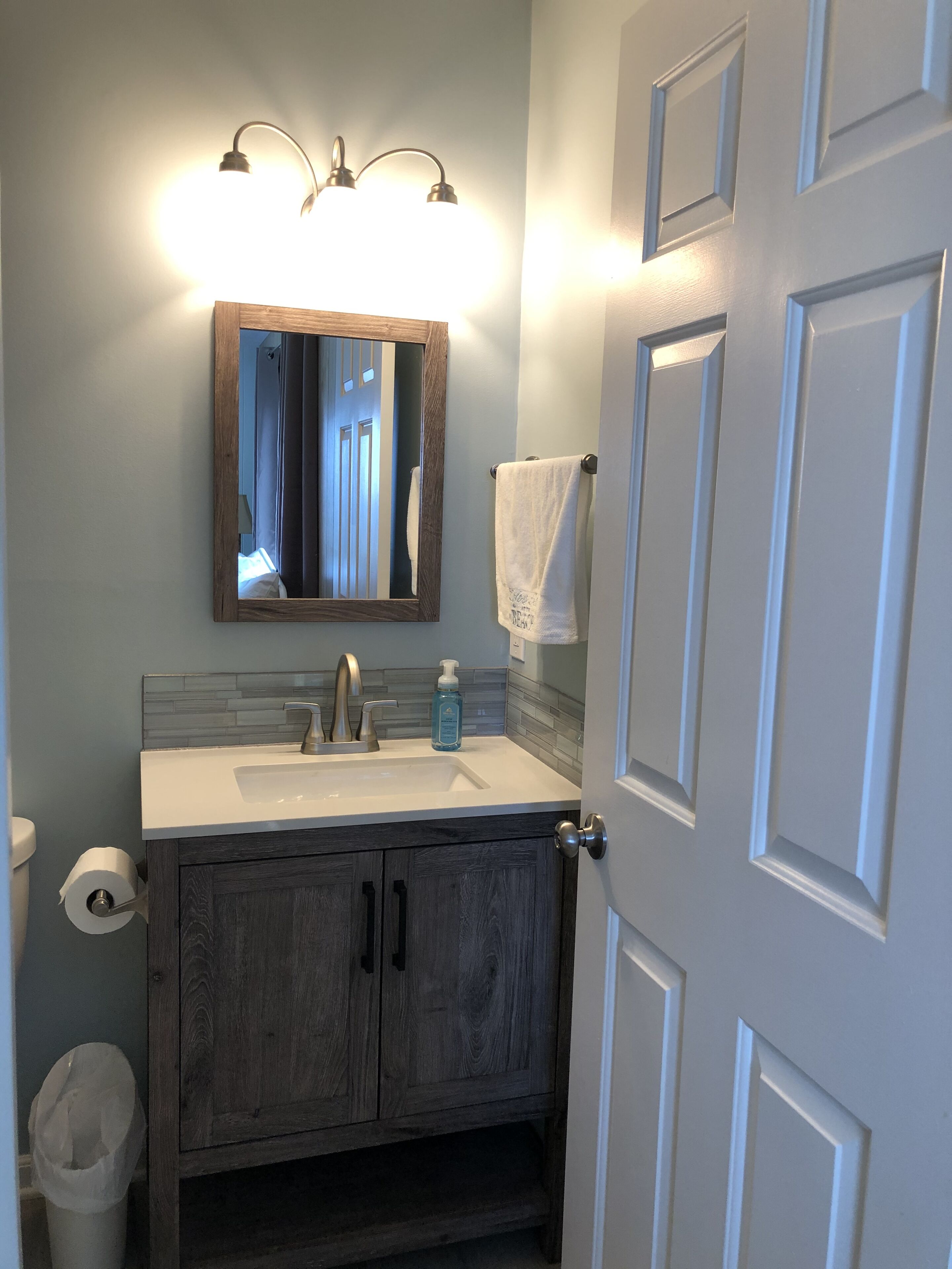 A bathroom with a wooden vanity, a mirror, a sink, and a towel rack.