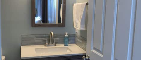 A bathroom with a wooden vanity, a mirror, a sink, and a towel rack.