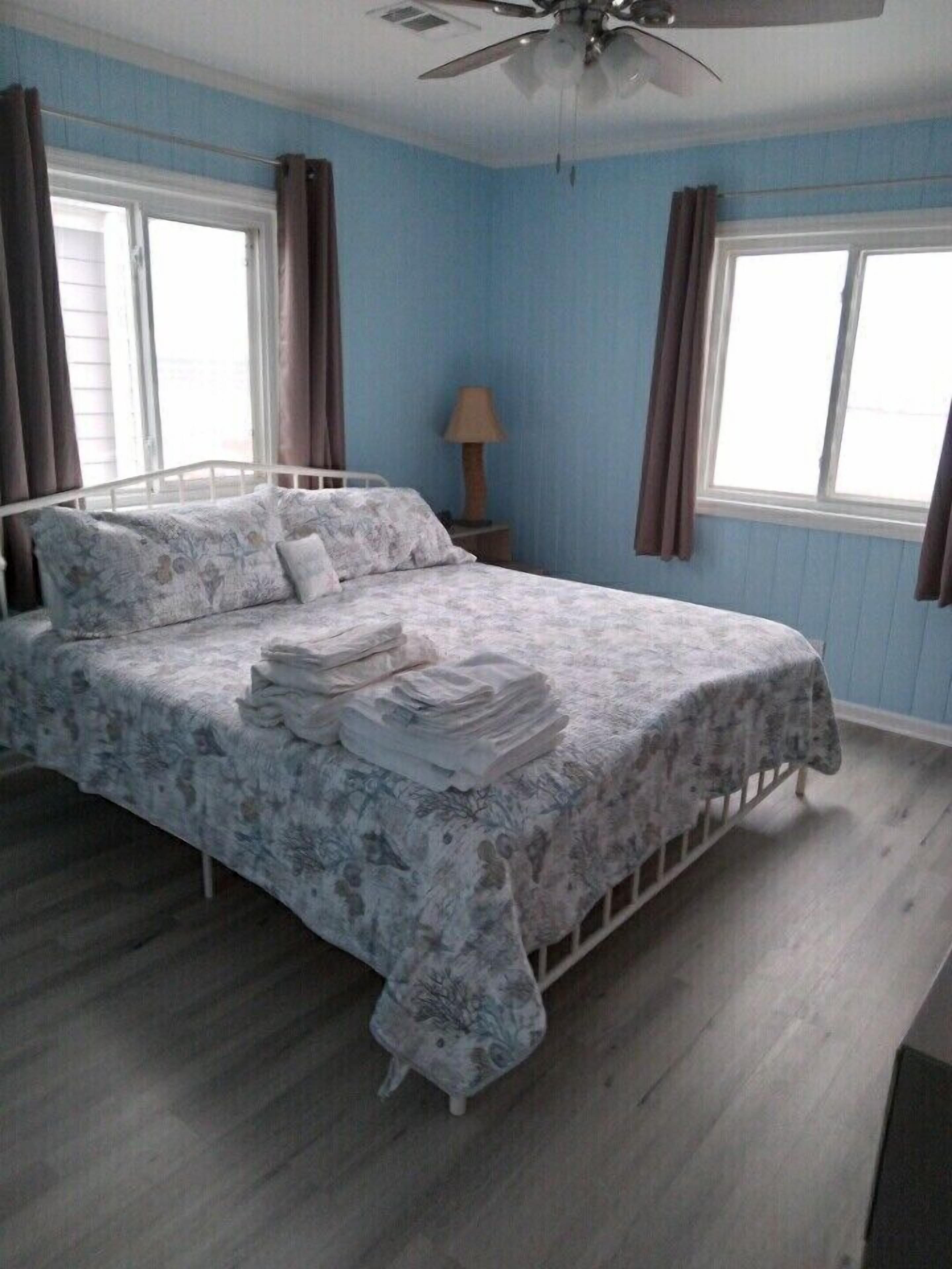 Ein Schlafzimmer mit Bett, Vorhängen, Deckenventilator und Fenster.