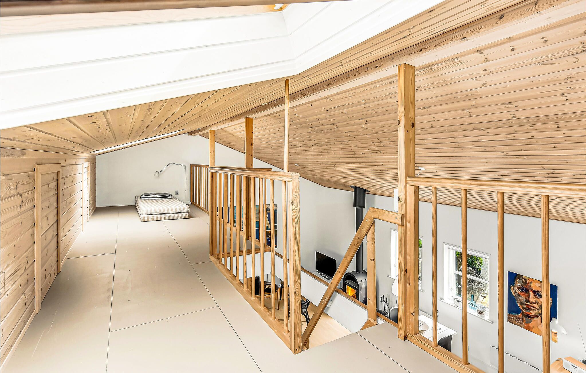 Une chambre moderne de style loft, avec un plafond en pente, des poutres en bois, un lit, un bureau avec un ordinateur et une cheminée.
