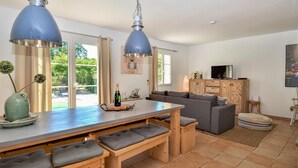 Una cocina moderna con una mesa de madera, bancos y lámparas colgantes azules.
