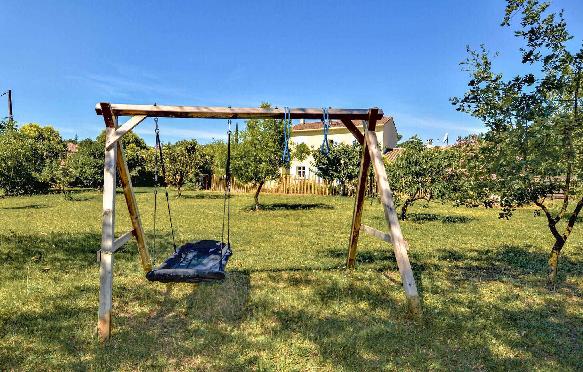 A wooden swing set in a grassy yard with a house in the background.