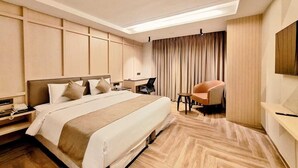 Quarto de hotel moderno com uma cama grande, uma escrivaninha, uma cadeira e uma televisão.