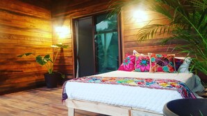 A cozy room with wooden walls, a bed with colorful bedding, and a potted plant.