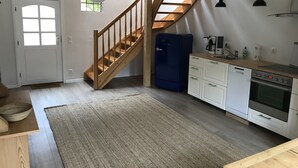Una cucina con una scala in legno, mobili bianchi, un frigorifero blu Bosch e un tavolo da pranzo in legno.