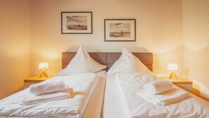 Ett hotellrum med två sängar, båda med vita lakan och kuddar, samt sänglampor.