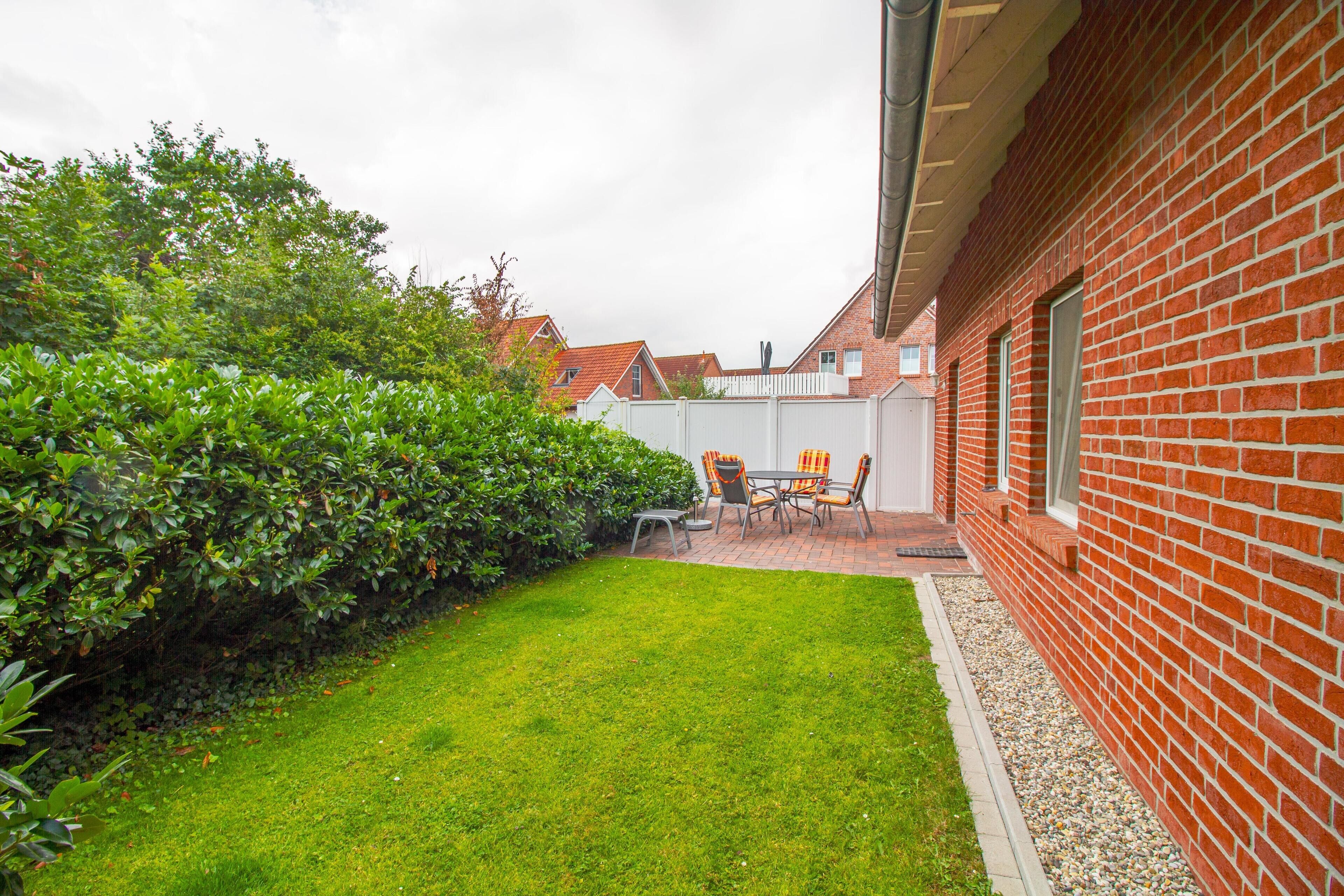 Una casa de ladrillo con un césped cuidado y un patio con mobiliario exterior.