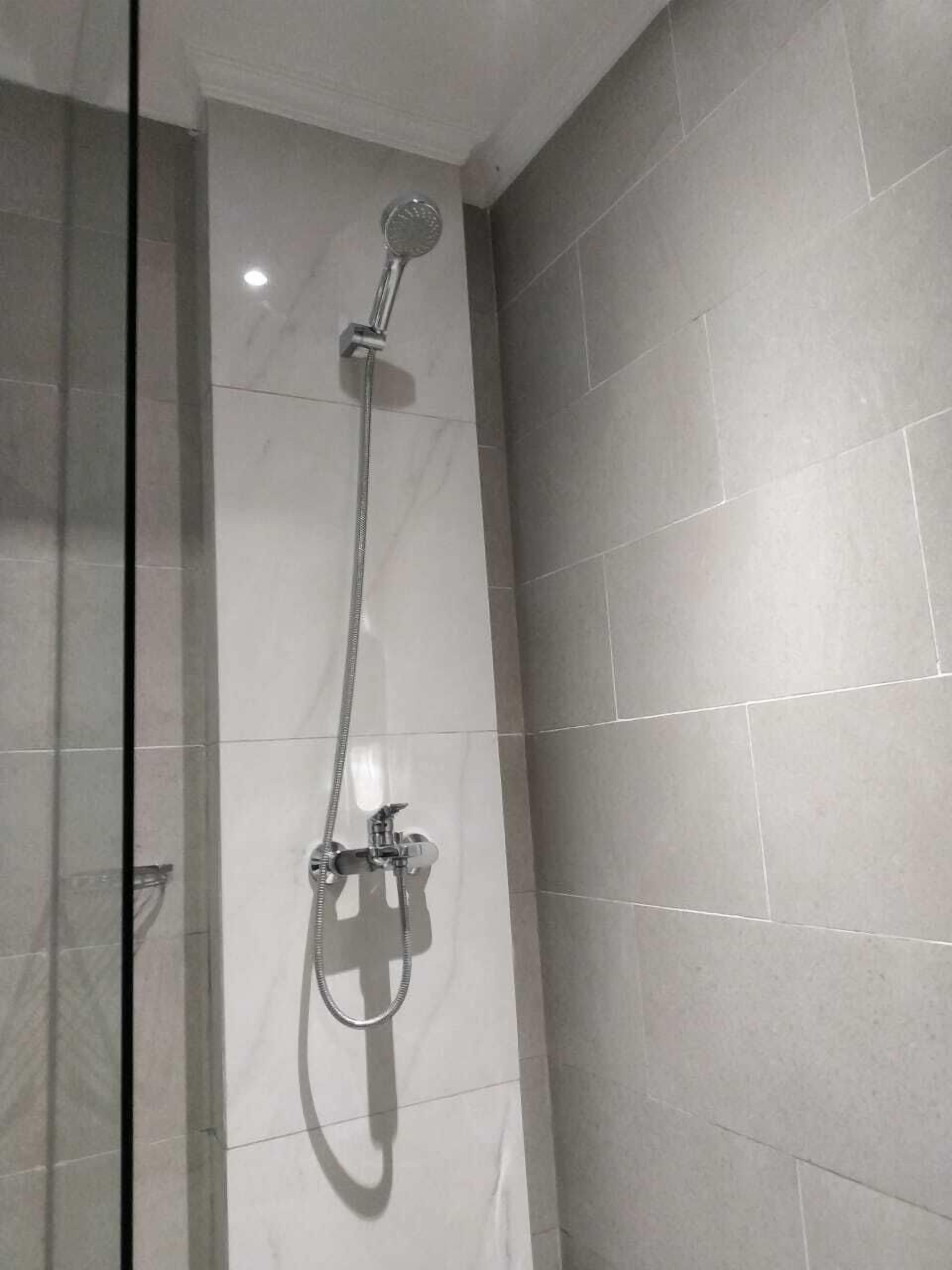 A shower with a handheld showerhead and a fixed wall-mounted showerhead.