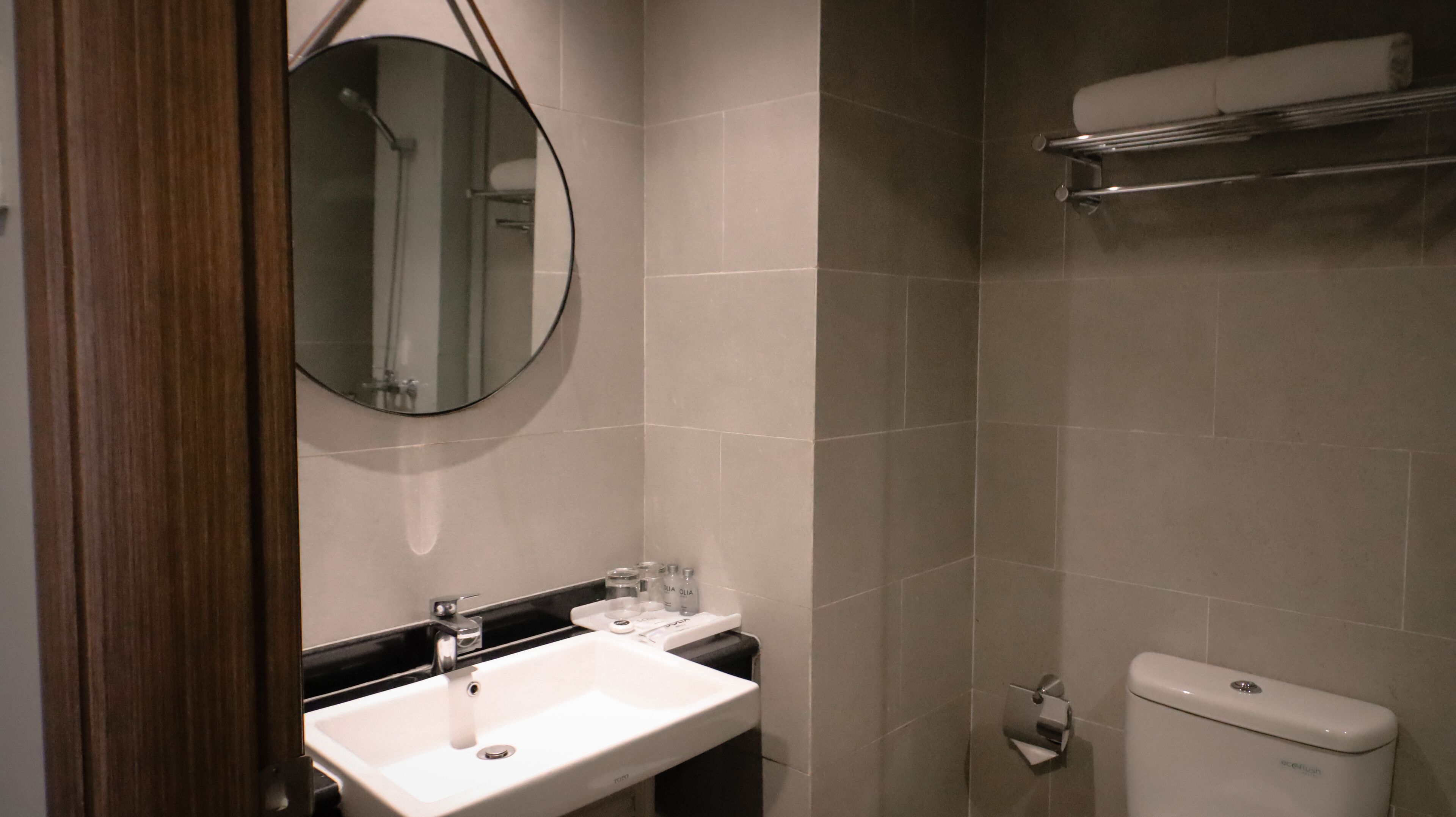 Une salle de bain avec un lavabo blanc, un miroir, des toilettes et un porte-serviettes.