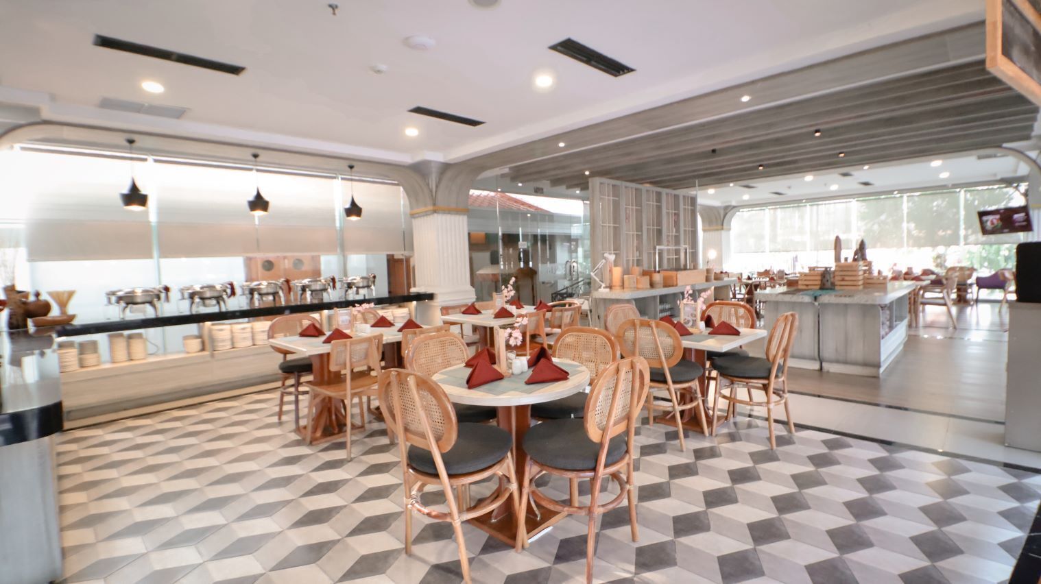 Un restaurante moderno con mesas redondas, sillas acolchadas y un suelo con estampado de cuadros.