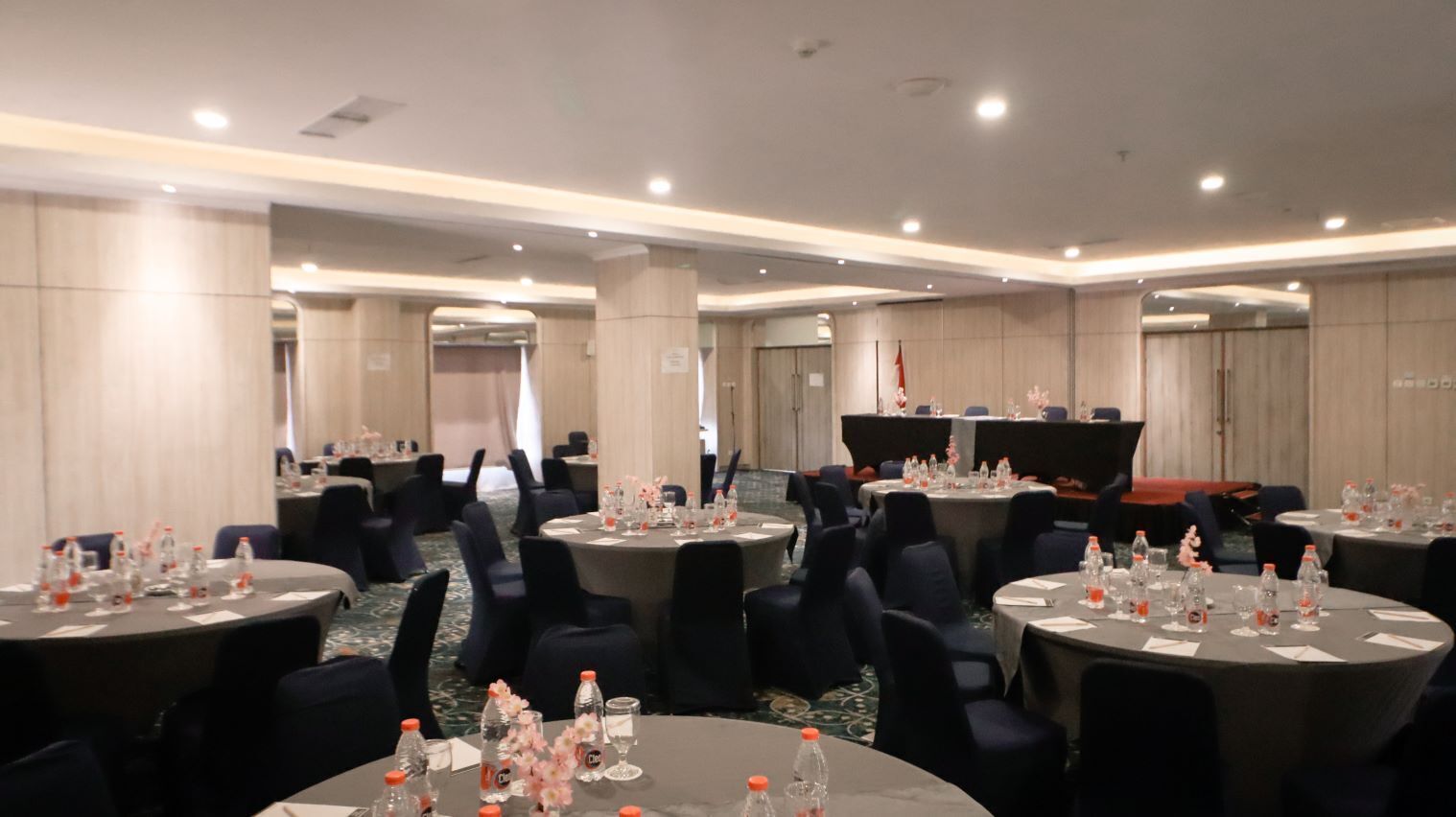 A conference room with round tables, chairs, and water bottles.