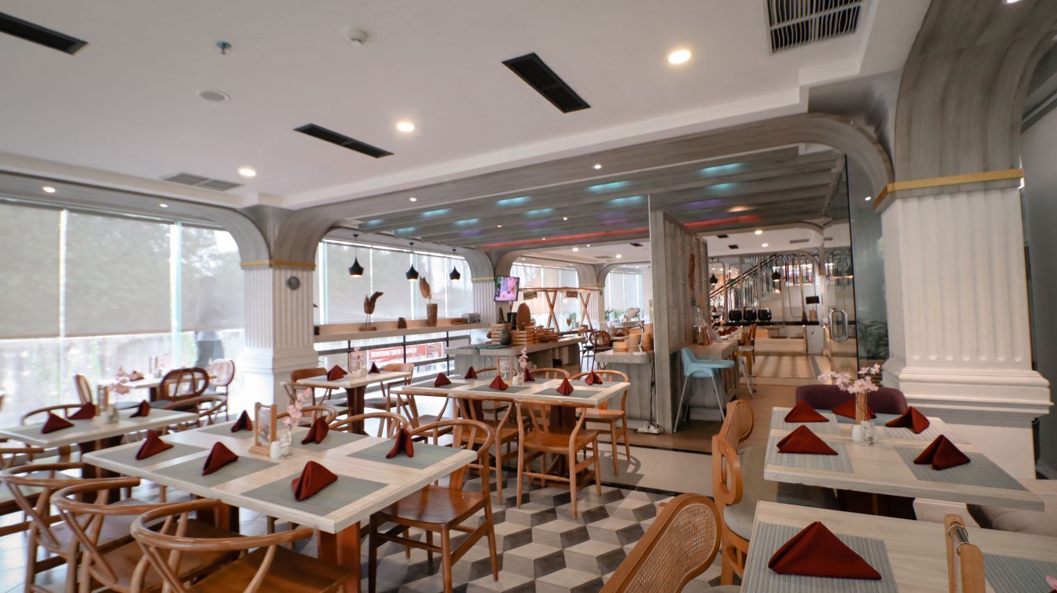 A restaurant with multiple tables and chairs, a bar area, and large windows.