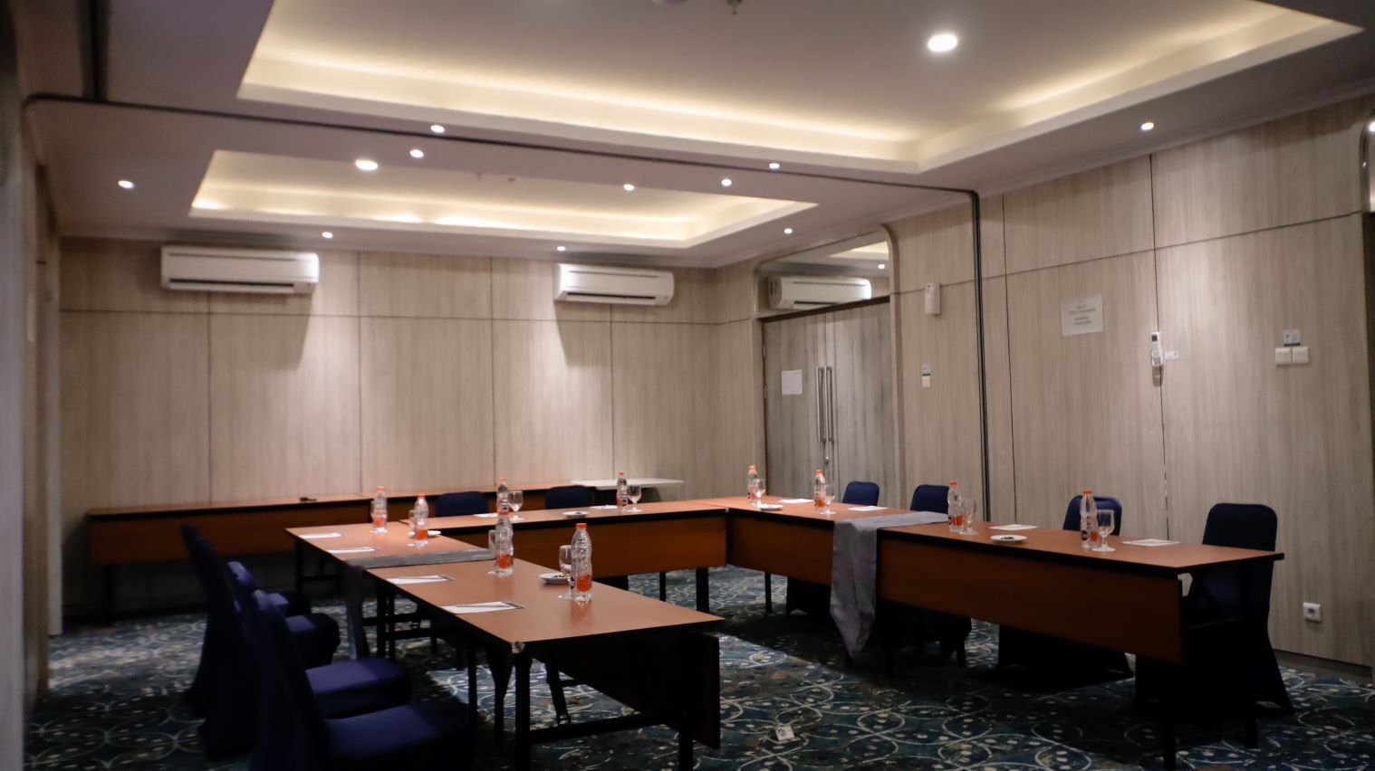 A conference room with a long table, chairs, and air conditioning units.