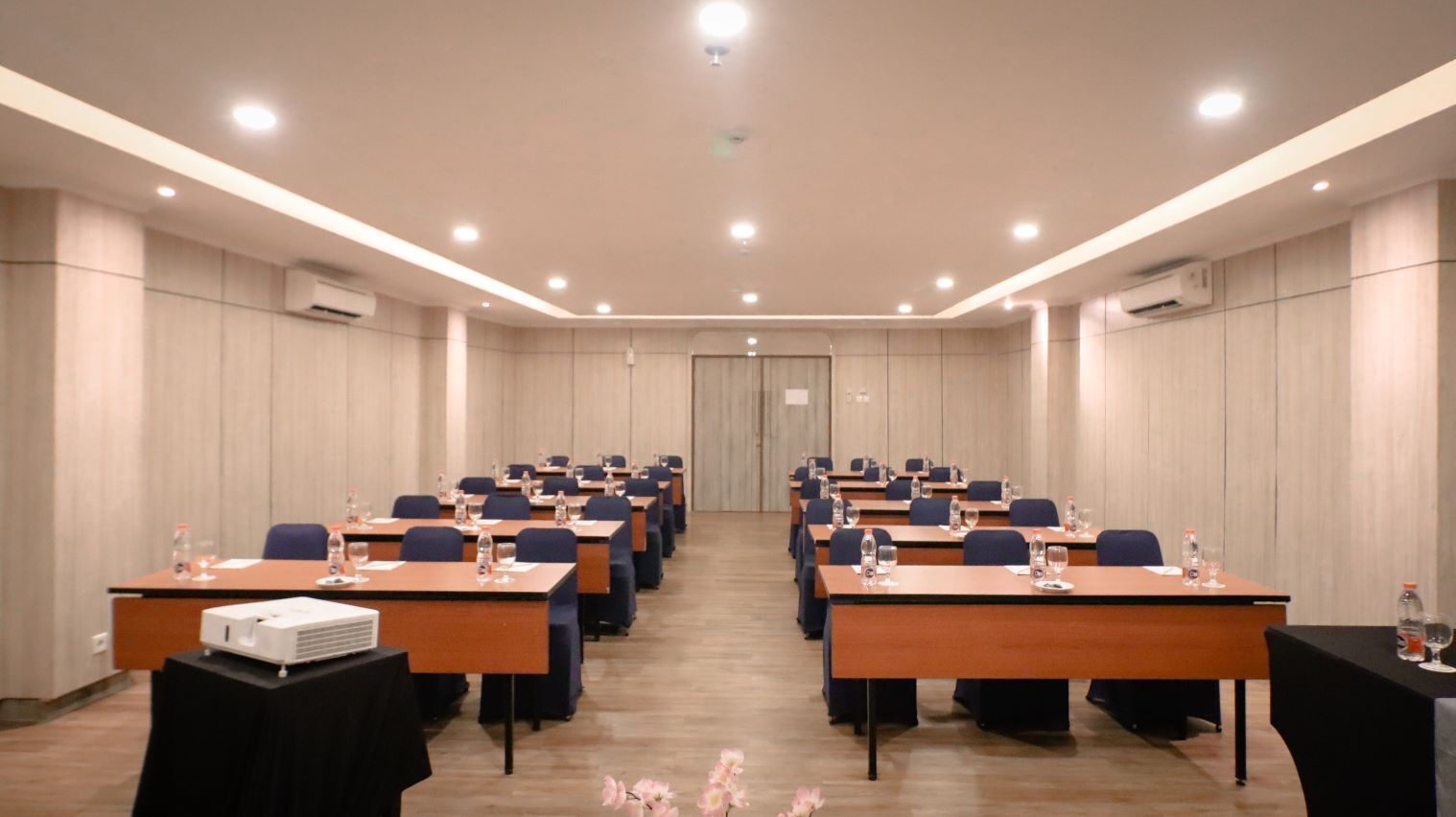 A conference room with rows of tables, chairs, and a projector.