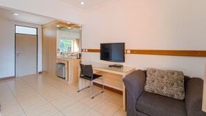 A modern hotel room with a kitchenette, a flat-screen TV, a sofa, and a dining area. - Applewood B&B (Bogor)