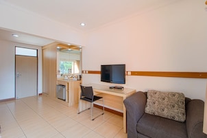 Habitación de hotel moderna con kitchenette, televisión de pantalla plana, sofá y zona de comedor.
