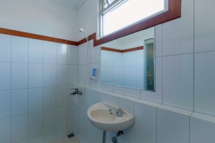 Un baño con azulejos blancos, un lavabo, un espejo y una ventana.