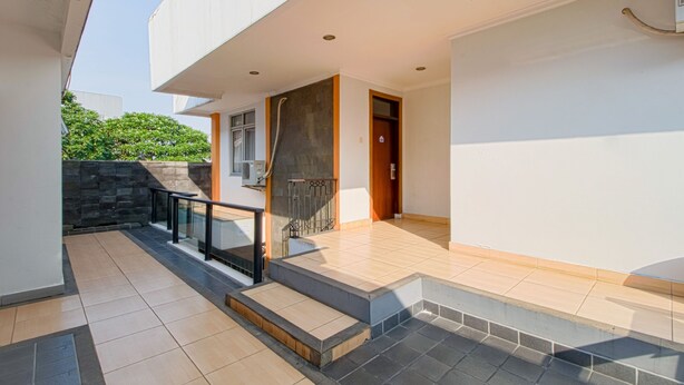 A modern house with a tiled patio, a staircase, and a door leading to the interior. - Applewood B&B (Bogor)
