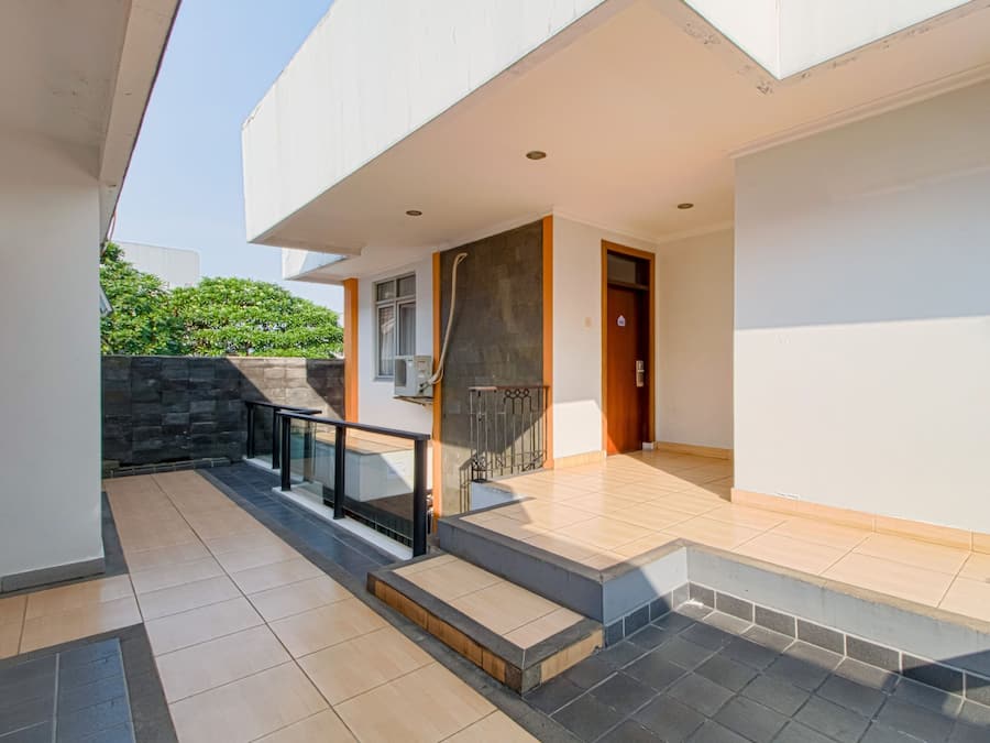 A modern house with a tiled patio, a staircase, and a door leading to the interior.