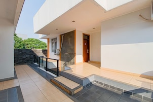 Una casa moderna con un patio empedrado, una escalera y una puerta que da al interior.