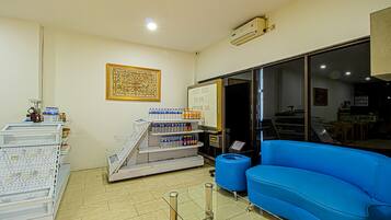 A room with a blue sofa, a whiteboard, shelves with various items, and a large window.