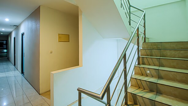 A modern hotel interior with a staircase, a hallway, and a door. - Bungur Inn Syariah (Jakarta)