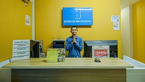 A reception desk with a sign for Bungur Inn Syariah, a no-smoking sign, and a calendar. - Bungur Inn Syariah (Jakarta)
