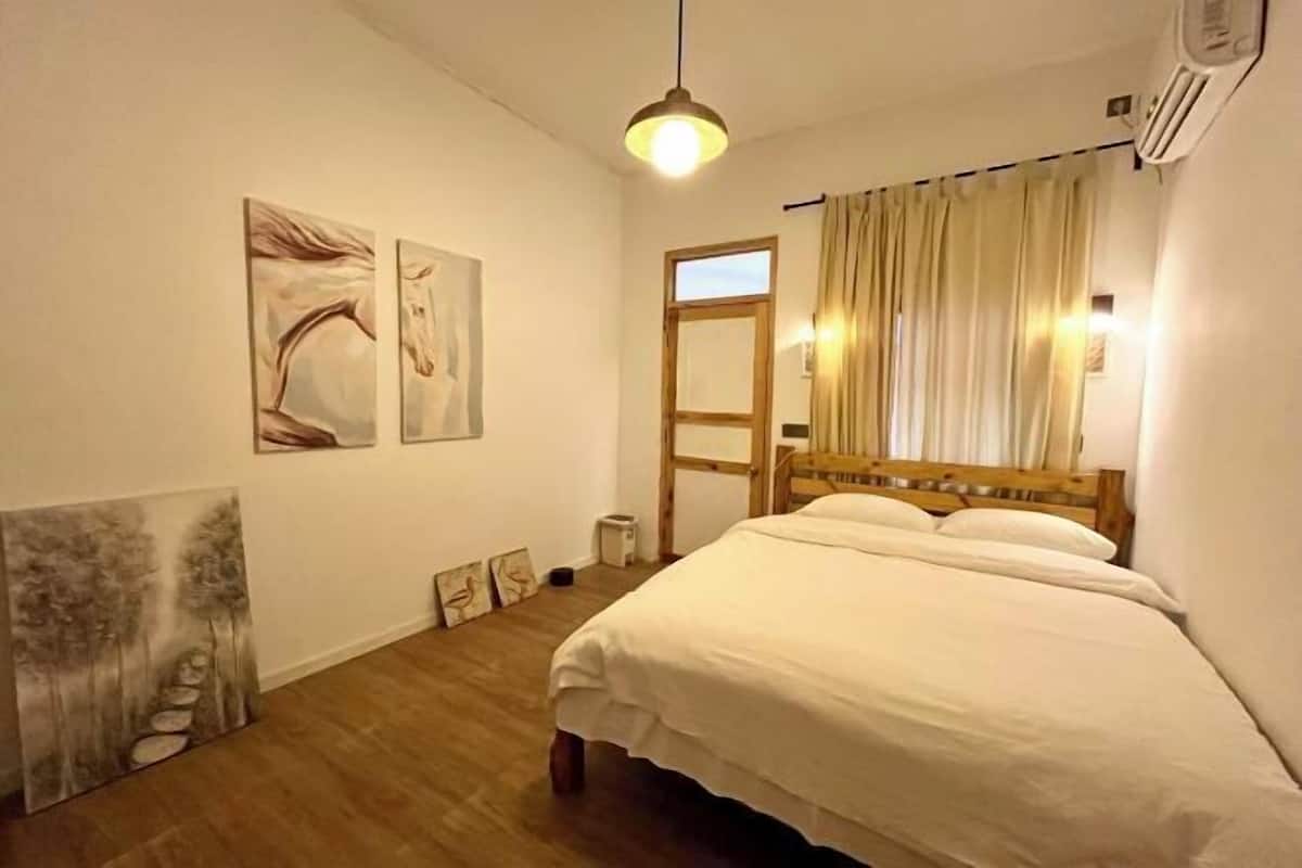 A bedroom with a wooden bed, a hanging light fixture, and artwork on the walls.