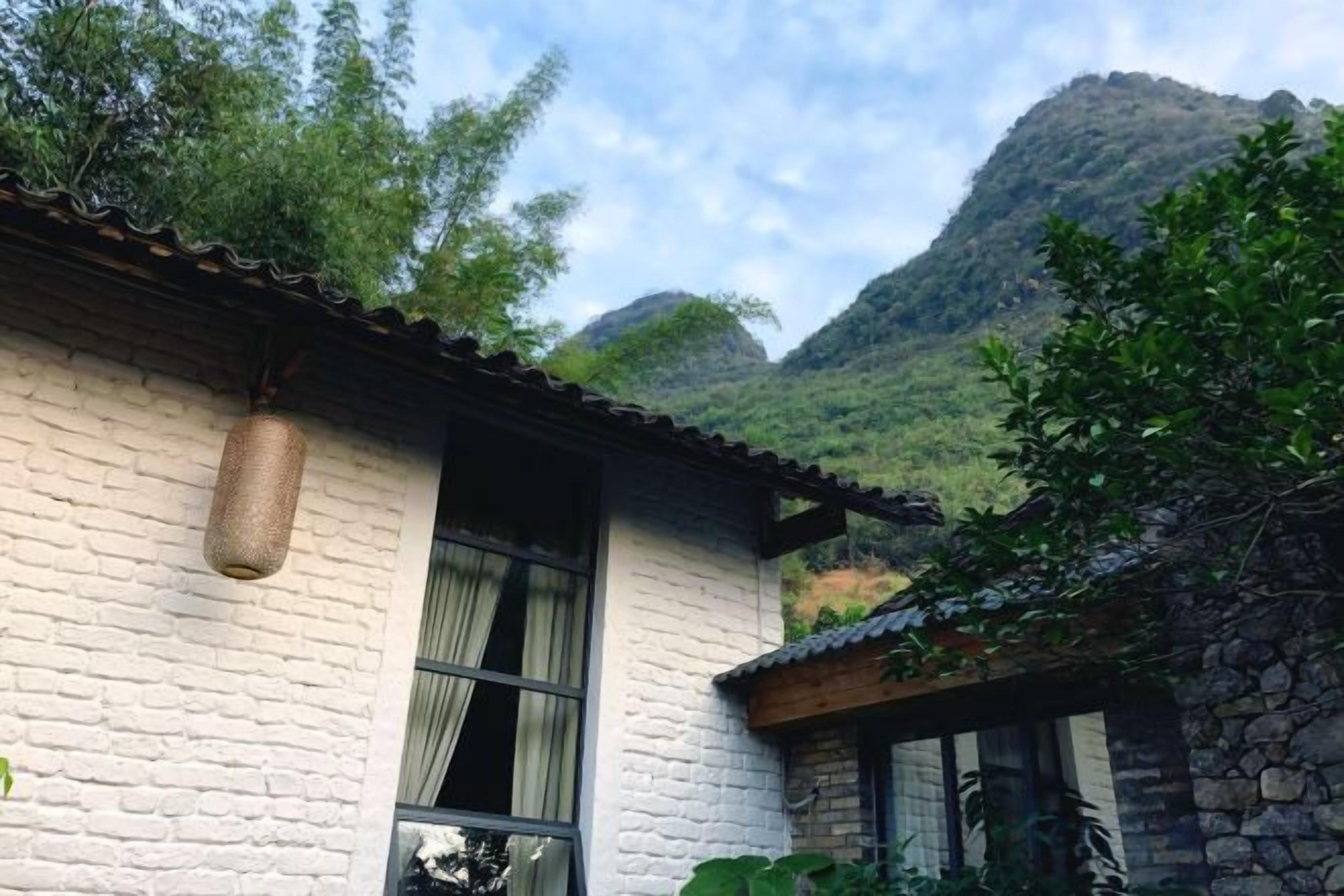 Un bâtiment traditionnel avec un mur en pierre, une jardinière suspendue et une fenêtre.