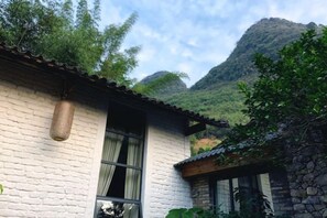 A traditional building with a stone wall, a hanging basket, and a window. - Zen Box House (Guilin)
