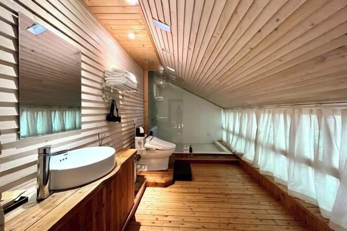 A wooden-paneled bathroom with a large mirror, a sink, and a toilet.