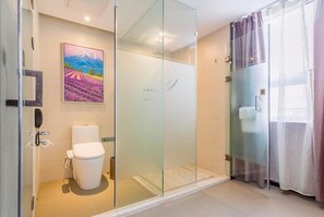 Un baño moderno con cabina de ducha de vidrio, inodoro y un cuadro de un paisaje.