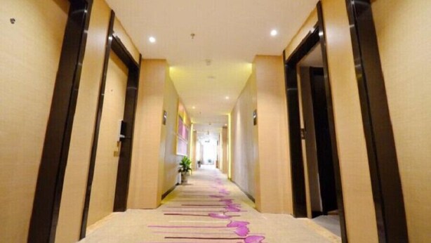 A hotel corridor with a long, narrow layout, featuring doors on both sides and a central walkway.