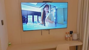 Un téléviseur fixé au mur affiche une image d’une femme dans le hall d’un hôtel.