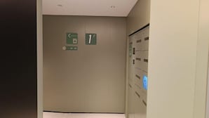 Un couloir avec un panneau indiquant la direction du premier étage et un ascenseur.