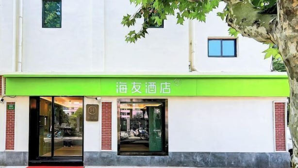 L’entrée d’un hôtel, avec un auvent vert et un tapis rouge.