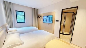 Une chambre d’hôtel avec deux lits, un téléviseur fixé au mur, une fenêtre avec des rideaux et une porte avec un panneau en verre.