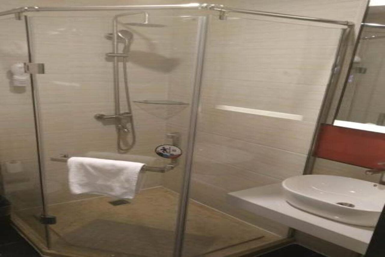 A glass-enclosed shower stall with a white sink and towel rack.