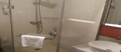 A glass-enclosed shower stall with a white sink and towel rack.