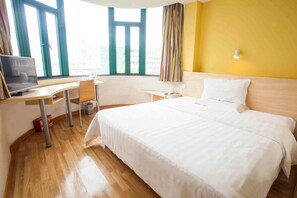 Une chambre d’hôtel avec un lit, un bureau avec un ordinateur portable, une chaise et une fenêtre avec des rideaux.
