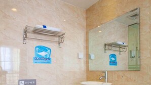 Ein Badezimmer mit Toilette, Waschbecken mit Spiegel darüber und Handtuchhalter.