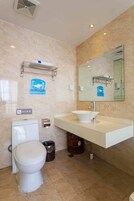 Un baño con inodoro blanco, lavamanos con espejo y un perchero para toallas.