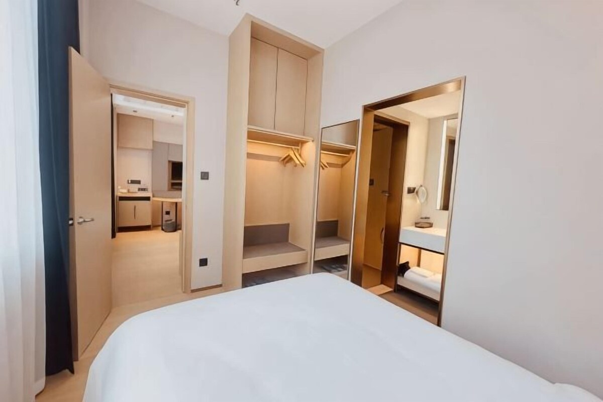 Ein Schlafzimmer mit Bett, begehbarer Kleiderschrank und einem Badezimmer inklusive Spiegel.